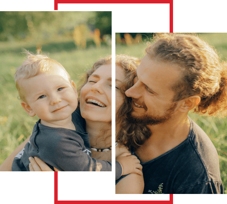 A man and woman holding a baby in the grass.